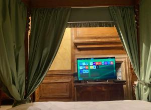 a bedroom with a bed with green curtains and a television at The Great Hall in Penrith