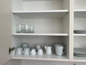 une rangée de tasses et de bols blancs sur une étagère dans l'établissement Studio ensoleillé avec balcon, à Lausanne