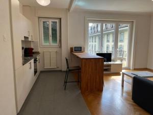 Habitación con cocina con escritorio y mesa. en Studio ensoleillé avec balcon en Lausana