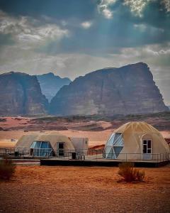 two tents in the desert with mountains in the background at Rum Mars luxury camp in Wadi Rum