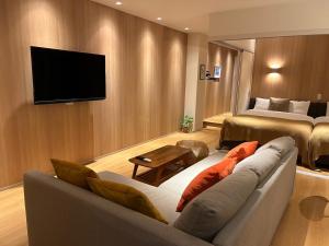 a living room with a couch and a tv on a wall at belle lune hotel hakata Suite Room 1 in Fukuoka