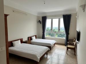 Hòa BìnhにあるThiên Bình Hotelのベッド2台と窓が備わるホテルルームです。