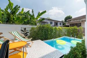 une piscine avec une table, des chaises et un frisbee dans l'établissement MIQ Ekkamai3_Pool Villa_3BR house, à Bangkok