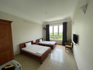 um quarto de hotel com duas camas e uma janela em Thiên Bình Hotel em Hòa Bình