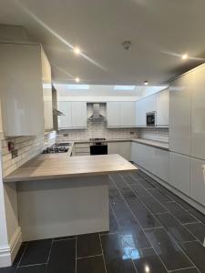 a large kitchen with white cabinets and a black tile floor at Bryn Road House in Sketty