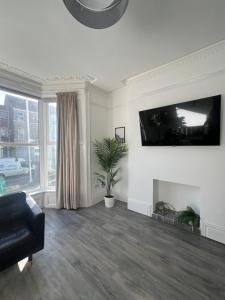 a living room with a fireplace and a tv on the wall at Bryn Road House in Sketty