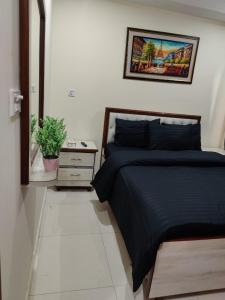 a bedroom with a black bed and a night stand at SR Apartments Islamabad in Islamabad