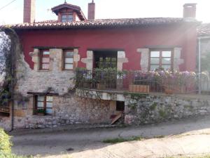 an old stone house with flowers on the balcony at La Portiella del Llosu in Pandiello