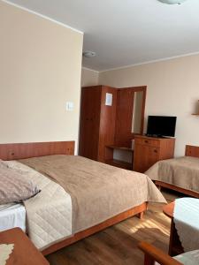 a bedroom with two beds and a flat screen tv at Chata Rybaka in Ustronie Morskie