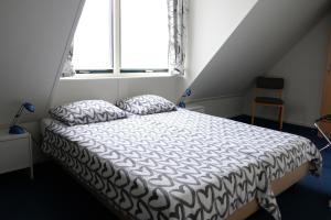 1 dormitorio con 1 cama con edredón blanco y ventana en Herberg de Roskam, en Uffelte