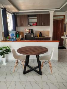 cocina con mesa de madera y 2 sillas en One bedroom unit with wi-fi & parking, en Nanyuki