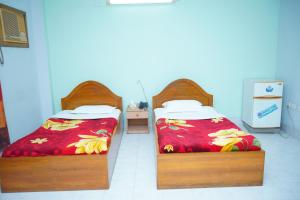 two beds sitting next to each other in a room at Rainbow Guest House in Sylhet
