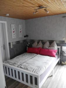 um quarto com uma cama branca e almofadas vermelhas em Eva's Home em Müllenbach