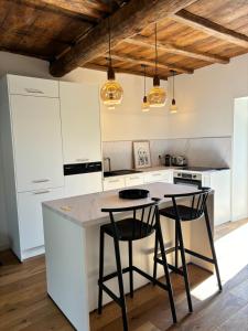 a kitchen with white cabinets and a island with two stools at CASA SAN MATTEU in Patrimonio