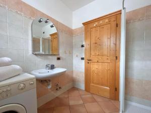 a bathroom with a sink and a wooden door at Appartamento Joemy in Livigno