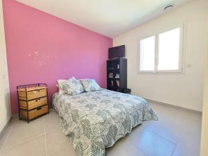 1 dormitorio con cama y pared de color rosa en Agréable maison de village avec piscine en Le Cailar