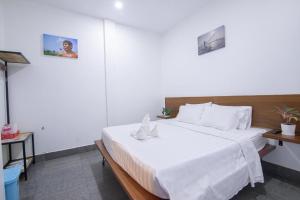 a bedroom with a large bed with white sheets at Pooltop Phnom Penh in Phnom Penh