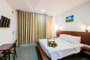 a bedroom with a bed and a table and a window at Pooltop Phnom Penh in Phnom Penh