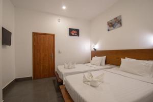 a bedroom with two beds with white sheets at Pooltop Phnom Penh in Phnom Penh
