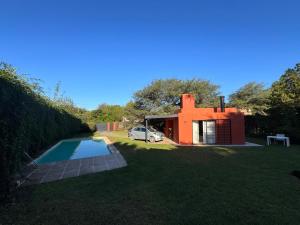 a house with a car parked next to a swimming pool at La casita anaranjá in Villa Allende