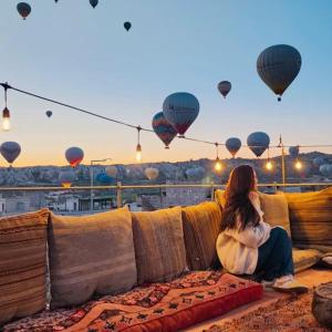 a woman sitting on a couch watching hot air balloons at Ala Stone Hotel in Goreme