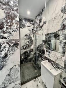 a black and white bathroom with a shower and a sink at Apartments near the sea in Odesa