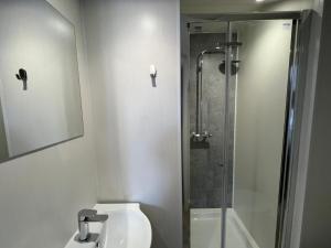 La salle de bains est pourvue de toilettes et d'une douche en verre. dans l'établissement We House One - Birmingham, à Birmingham