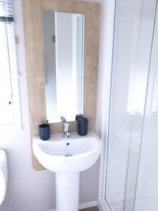 a bathroom with a white sink and a mirror at 16 anglers acre luxury hot tub break tattershall lakes in Tattershall +4 photos