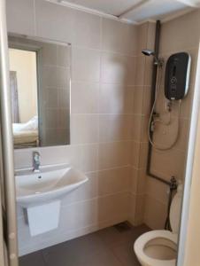 een badkamer met een wastafel, een toilet en een spiegel bij Sweet Homestay Golden Shower Apartment in Melaka
