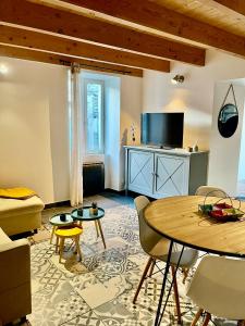 a living room with a table and a tv at GITE LES ROMAINS 2/4p au coeur du village classé d'ALBA LA ROMAINE in Alba-la-Romaine