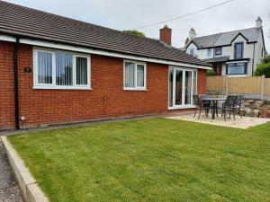 a red brick house with a table and chairs in a yard at 3-Bed bungalow near Conwy valley close to Castle in Colwyn Bay