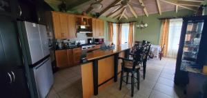 a kitchen with a refrigerator and a counter with stools at 3BR 3BA, Luxury Villa with Pool House Access in Olveston