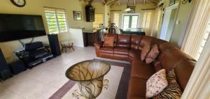 a living room with a leather couch and a television at 3BR 3BA, Luxury Villa with Pool House Access in Olveston