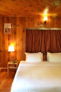 um quarto com uma cama branca num quarto de madeira em Sinchula Villa em Paro
