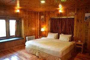 Cette chambre en bois comprend un grand lit. dans l'établissement Sinchula Villa, à Paro