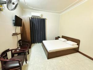 a bedroom with a bed and a tv and chairs at Đình Vũ 3 Motel in Hai Phong