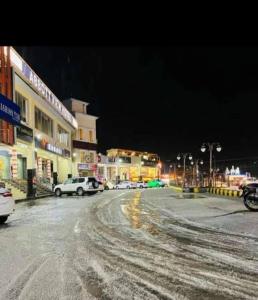 une rue enneigée de la ville la nuit avec des voitures garées dans l'établissement Abbotabad view hotel, à Abbottabad
