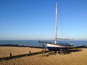 a boat sitting on the beach near the ocean at Stylish Victorian Cottage, 2mins from Whitstable Harbour & Shops in Whitstable +13 photos