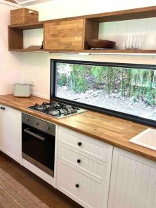 a kitchen with a stove and a large window at Whispering Palms, Luxury Tiny Home in Crabbes Creek