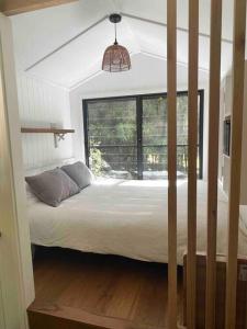 a bedroom with a bed and a large window at Whispering Palms, Luxury Tiny Home in Crabbes Creek