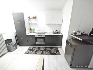 a kitchen with white cabinets and a rug on the floor at Urlaub am Rhein Speyer Hockenheim in Altlußheim