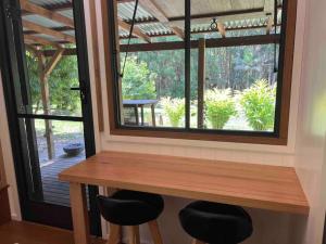 a table and two stools in front of a window at Whispering Palms, Luxury Tiny Home in Crabbes Creek