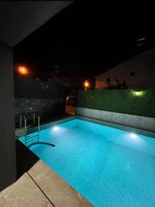 a large swimming pool at night with lights on it at Dublex havuzlu villa in Erdemli