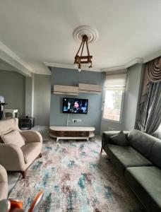 sala de estar con sofá y TV de pantalla plana en Dublex havuzlu villa, en Erdemli