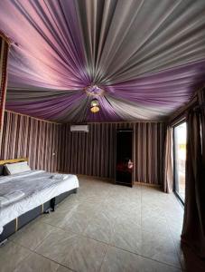 - une chambre avec un lit au plafond violet dans l'établissement Desert star camp, à Wadi Rum