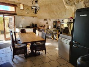 a kitchen with a wooden table and a refrigerator at La grotte in Bourré