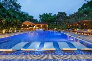 a large swimming pool with chairs and a resort at Green Mansions Jungle Resort in Sauraha