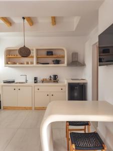 a kitchen with white cabinets and a table and chairs at Alonia Suites in Naousa