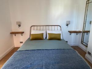 a bed with two pillows and a blue blanket at Bright new flat in Battersea in London