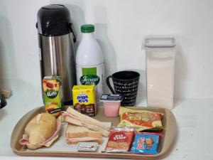 uma mesa com uma bandeja de comida e uma sanduíche e leite em Villa Fátima Hostel GRU em Guarulhos